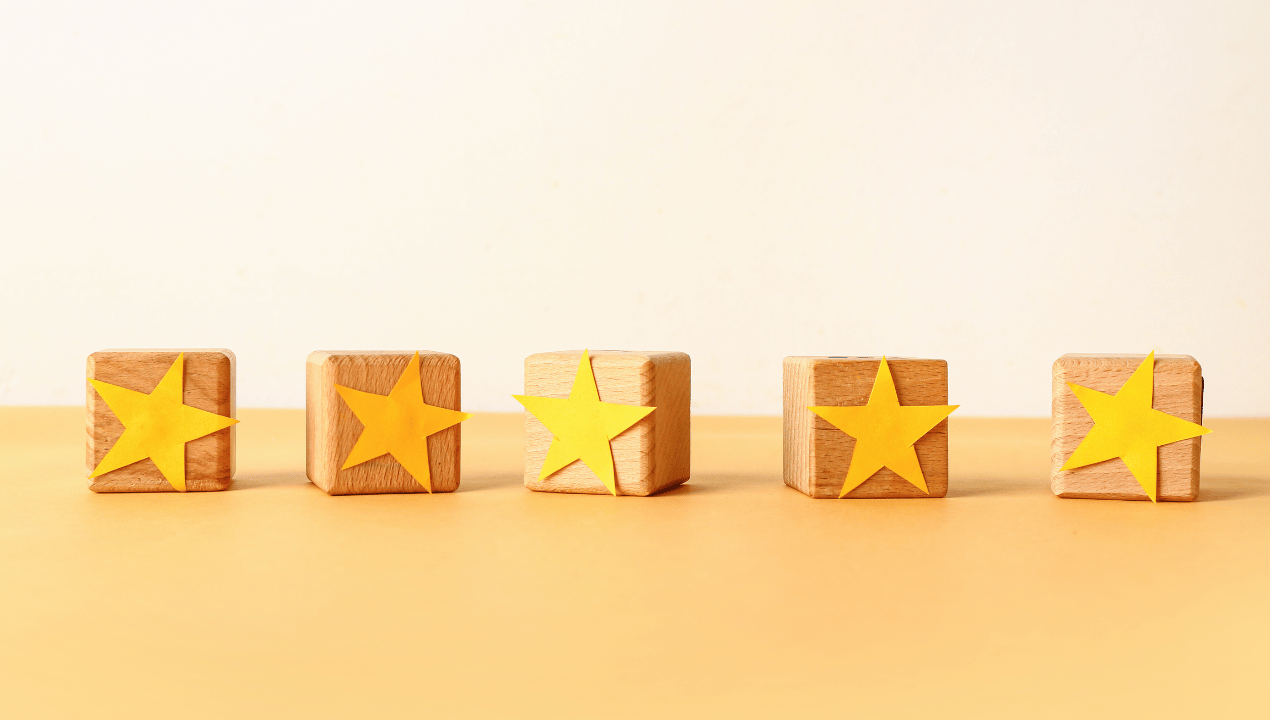 Five wooden blocks decorated with yellow stars on a warm neutral background